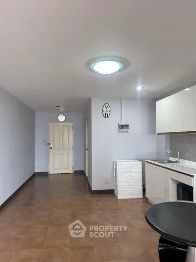 Spacious open-plan kitchen with modern cabinetry and tiled flooring in a bright apartment.