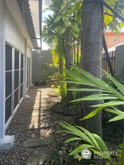 Charming garden pathway with lush greenery and pebble stone design in a serene residential setting.