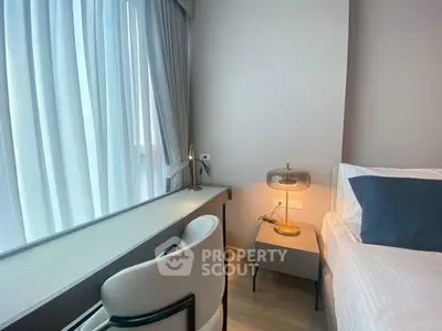 Modern bedroom with stylish decor and large window offering natural light.
