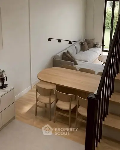 Modern living room with stylish dining area and cozy sofa, featuring elegant wooden furniture and natural light.