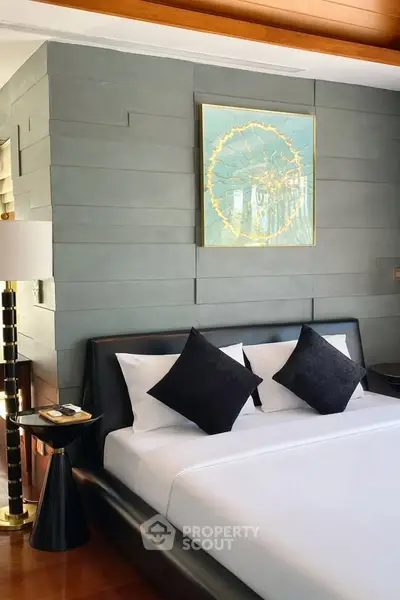 Luxurious bedroom with modern decor and elegant artwork, featuring a sleek black bed and stylish lighting.