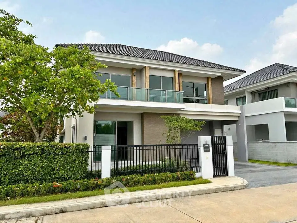 Modern two-story house with sleek design and lush greenery in a serene neighborhood.
