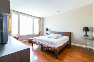 Spacious bedroom with modern furnishings and large windows for natural light.