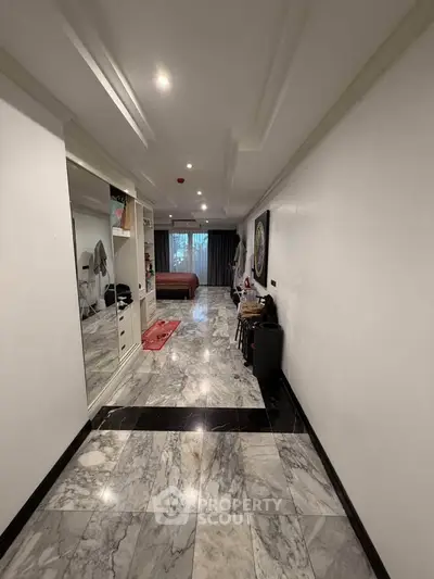 Spacious hallway leading to a cozy bedroom with marble flooring and elegant decor.