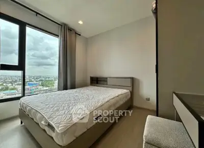 Modern bedroom with large window offering city view, featuring a comfortable bed and minimalist decor.
