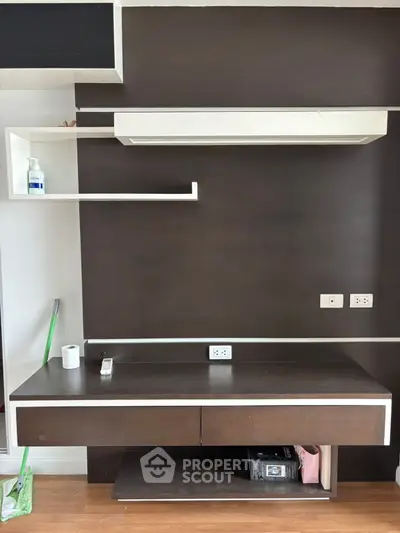 Modern study area with sleek dark wood desk and shelves, featuring built-in power outlets.
