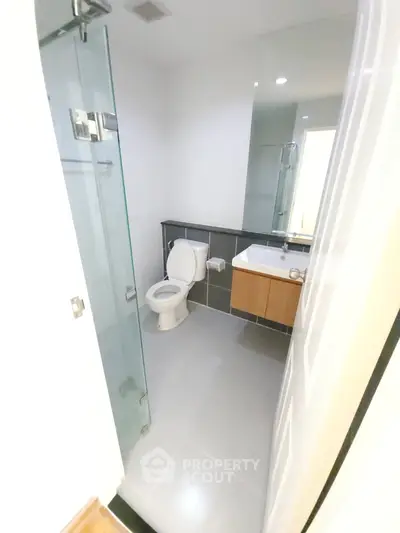 Modern bathroom with glass shower and sleek fixtures in contemporary home.