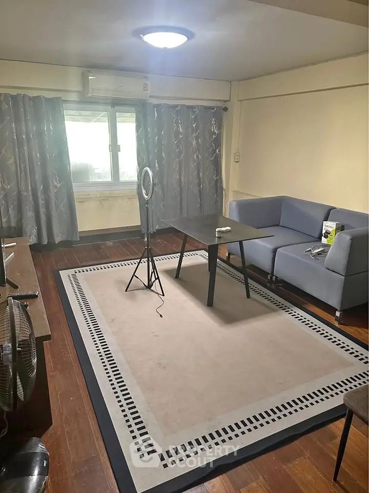 Spacious living room with modern decor and natural light, featuring a stylish rug and comfortable seating.