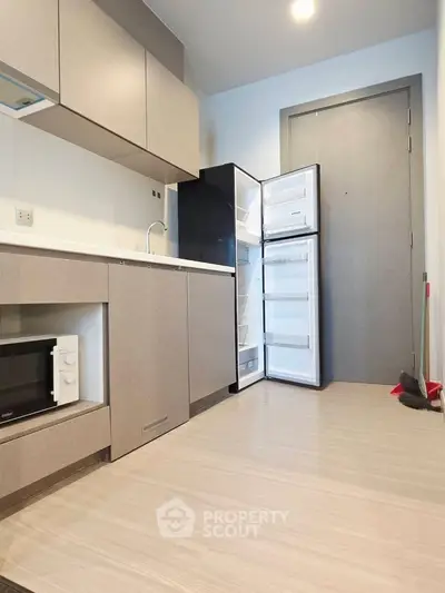Modern kitchen with open fridge and microwave in sleek apartment