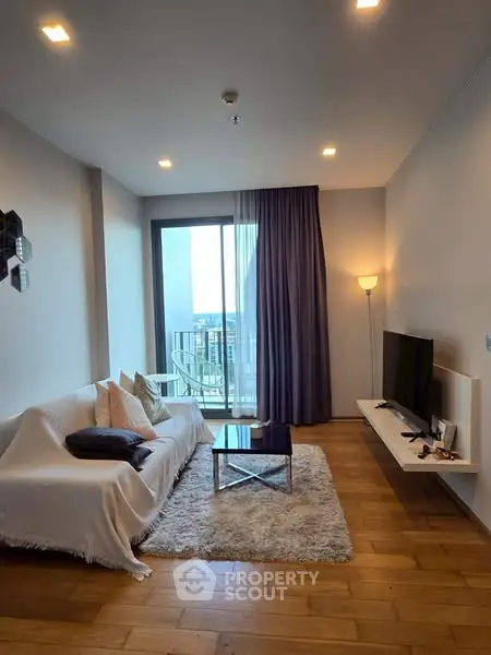 Modern living room with cozy decor and city view balcony access.