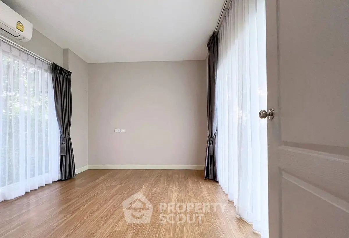 Spacious empty room with large windows and wooden flooring