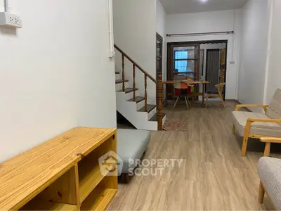 Charming living room with wooden flooring and staircase, cozy seating, and dining area.