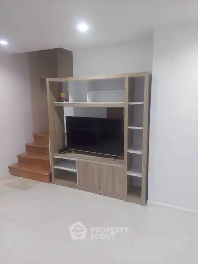Modern living room with stylish TV stand and wooden staircase