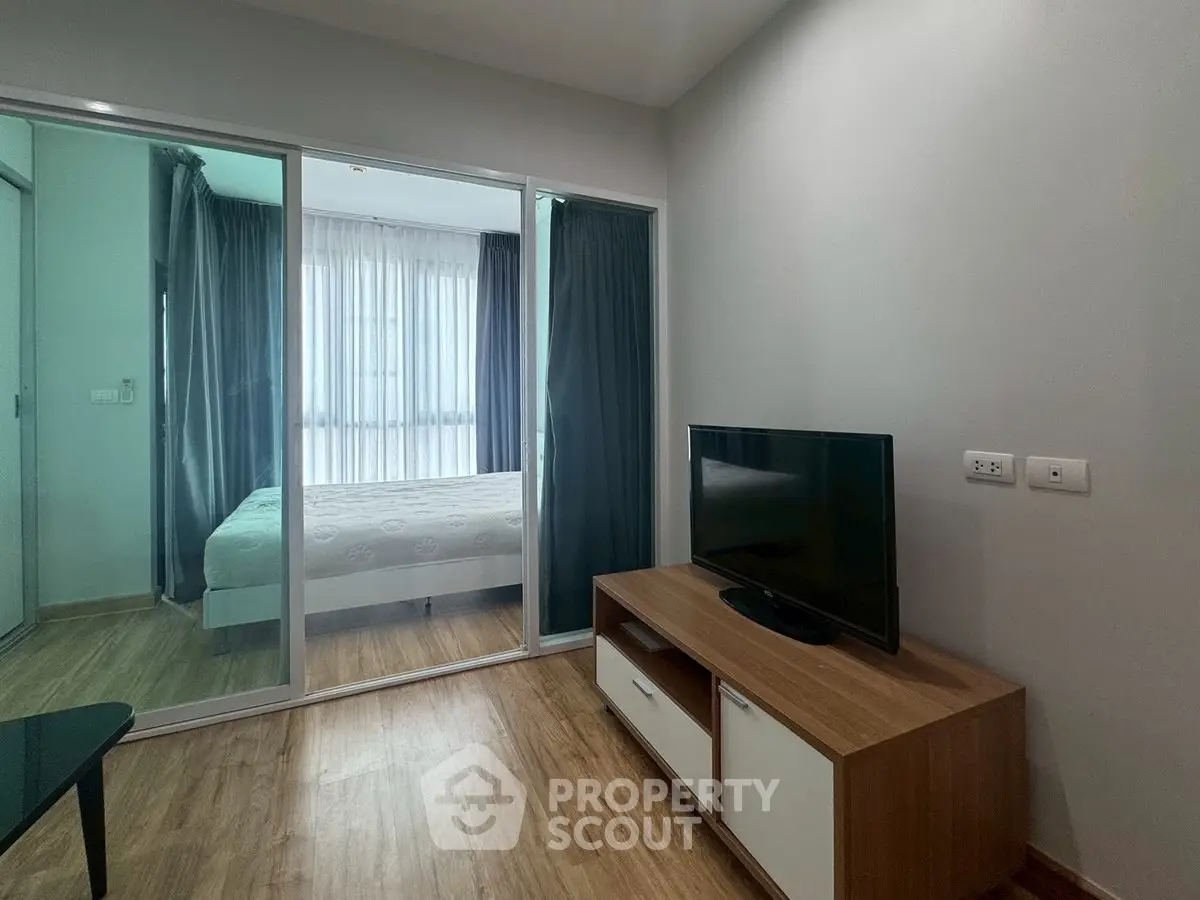 Modern bedroom with glass partition and cozy TV area, perfect for urban living.