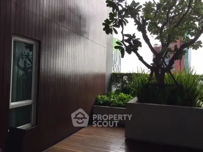 Stylish urban balcony with lush greenery and wooden decking, perfect for relaxation and city views.