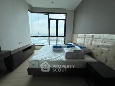 Spacious bedroom with large window offering stunning city views in modern apartment.