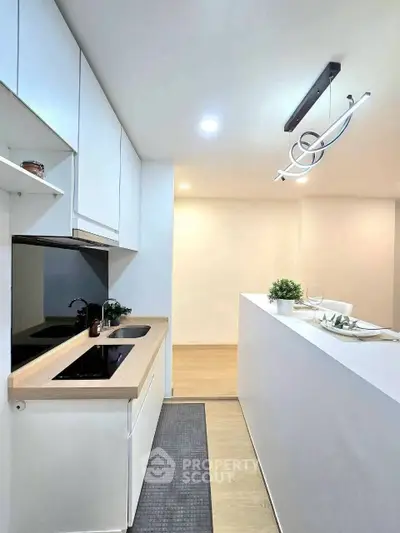 Modern kitchen with sleek design and open layout, featuring stylish lighting and minimalist decor.