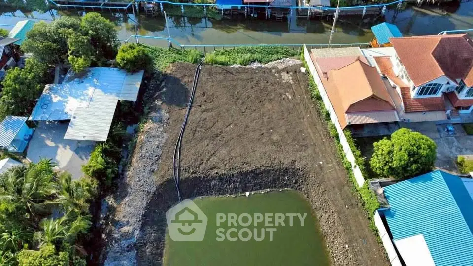 Aerial view of a residential plot with adjacent water body, ideal for development.