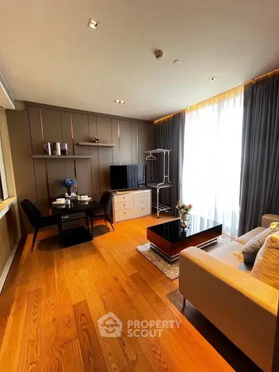 Modern living room with wooden flooring, stylish furniture, and ample natural light from large windows.
