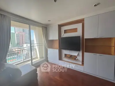Spacious living room with built-in TV unit and balcony view in modern apartment
