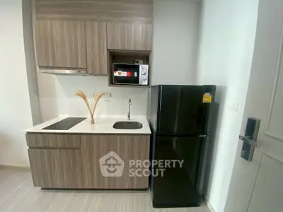 Modern compact kitchen with sleek cabinetry and appliances in a stylish apartment.