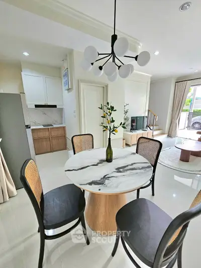 Modern dining area with elegant marble table and stylish lighting in open-plan living space.