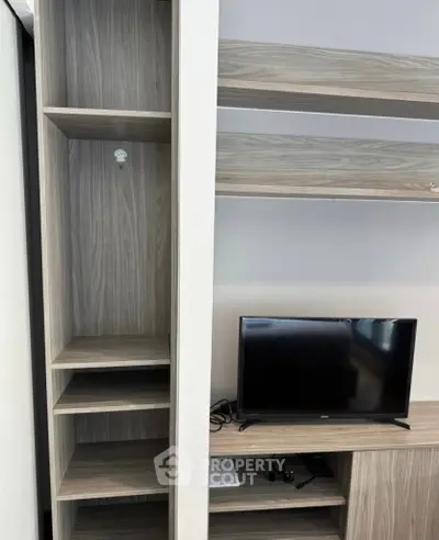 Modern living room with built-in wooden shelves and a compact TV setup.