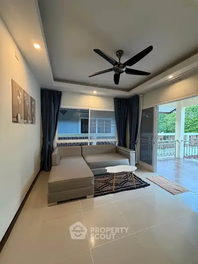 Spacious living room with modern decor and large windows opening to a balcony with a view.