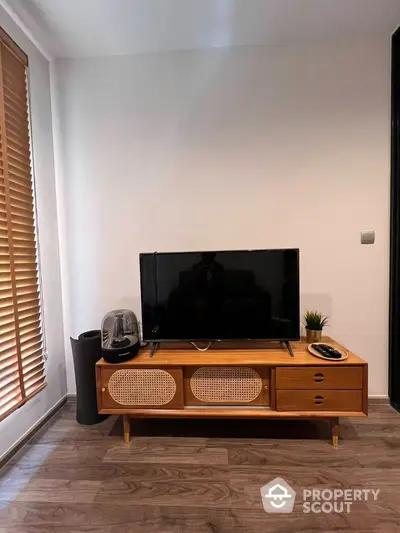 Cozy living room with modern wooden TV stand, large flat-screen TV, and stylish blinds, perfect for relaxing and entertainment.