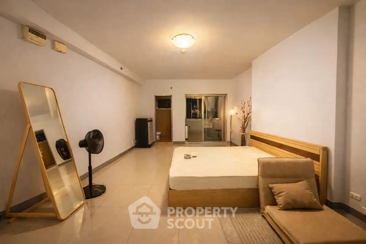 Spacious bedroom with modern decor and minimalist design, featuring a large mirror and cozy lighting.