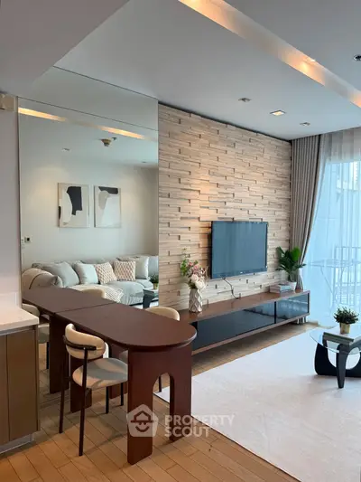 Modern living room with stylish decor and wall-mounted TV, featuring a cozy seating area and elegant dining table.
