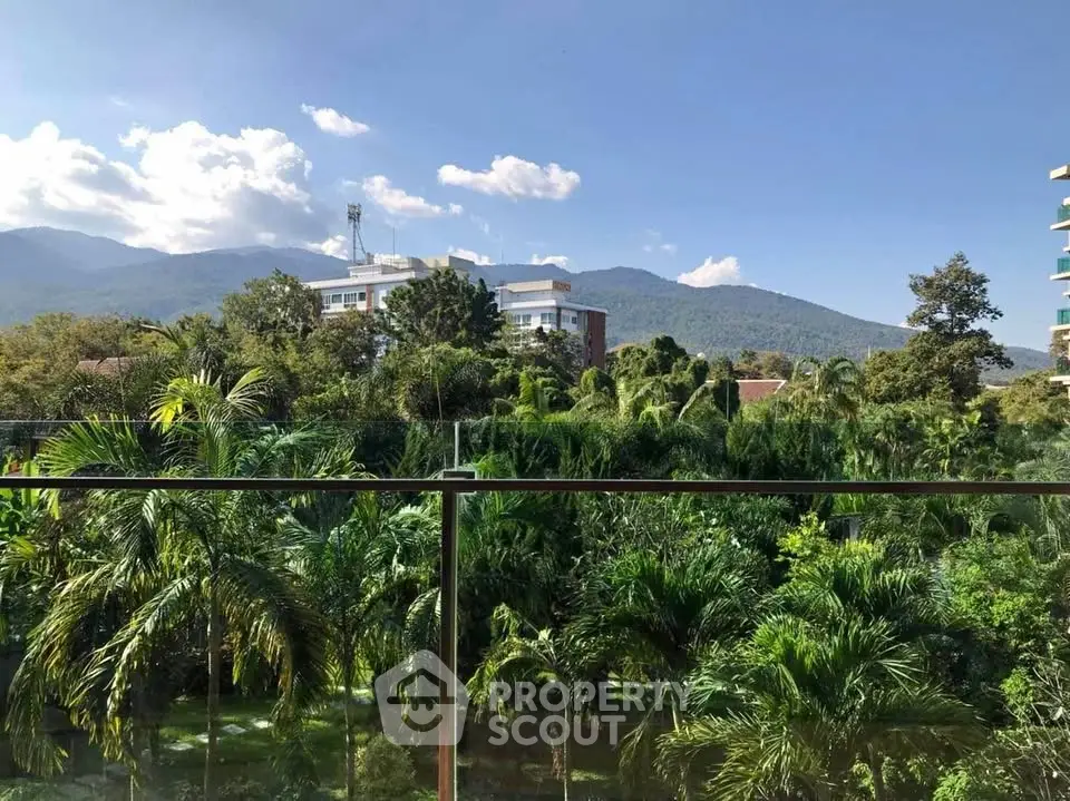 Stunning view from balcony overlooking lush greenery and distant mountains.