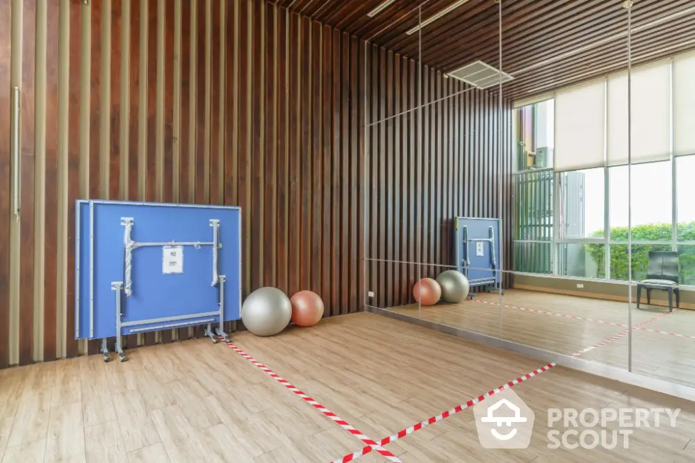 Modern gym with mirrored walls and exercise equipment in luxury apartment complex.