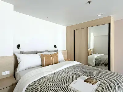 Modern bedroom with stylish decor and mirrored wardrobe in a cozy apartment.