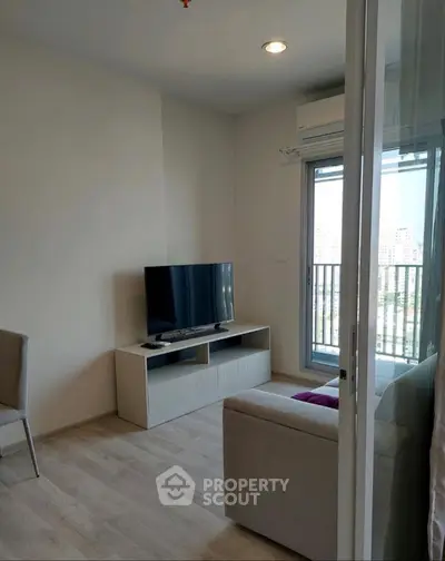 Modern living room with balcony view, featuring sleek TV setup and cozy seating area.