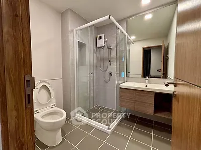 Modern bathroom with glass shower enclosure and sleek vanity in contemporary apartment.