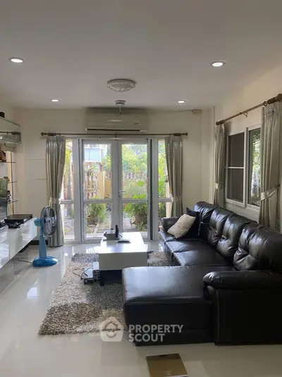 Spacious living room with large windows and modern leather sofa