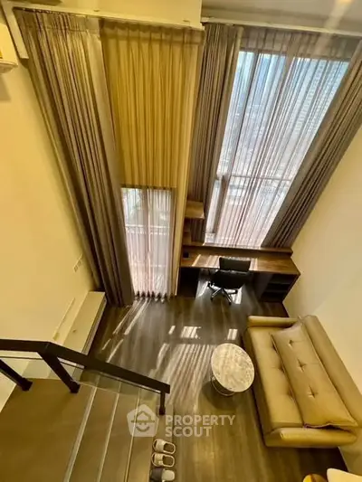 Modern loft-style living room with high ceilings and large windows offering city views.