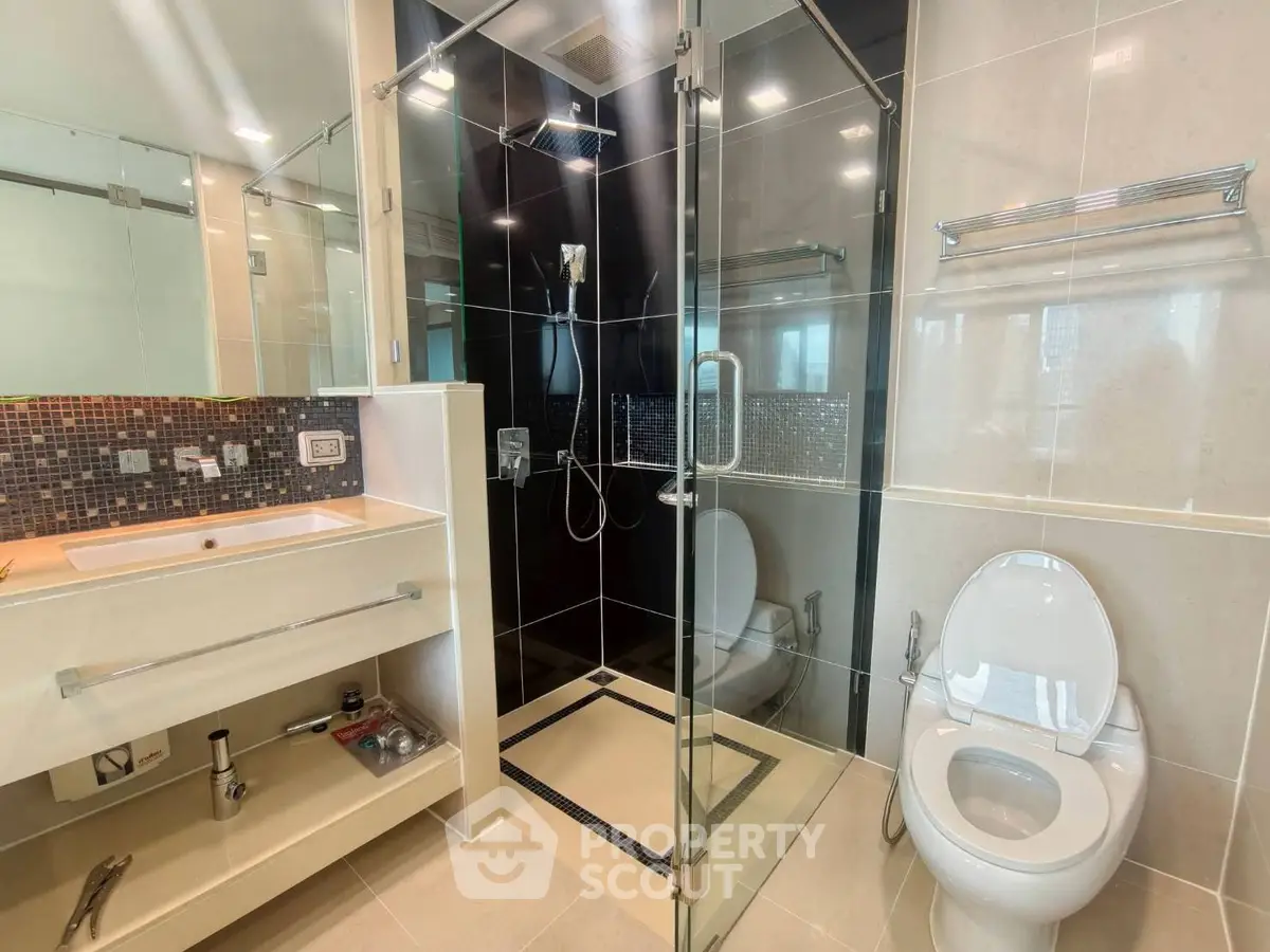 Modern bathroom with glass shower and sleek fixtures in luxury apartment.