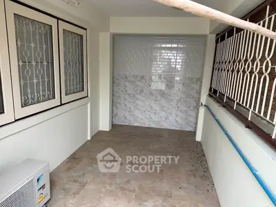 Spacious tiled balcony with secure window grills and air conditioning unit