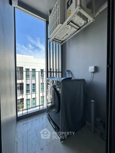 Modern laundry area with washing machine and city view in high-rise apartment.