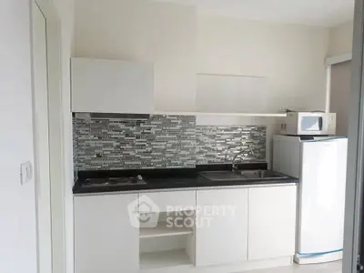 Modern compact kitchen with sleek white cabinets and mosaic backsplash