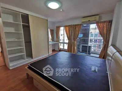 Spacious bedroom with large windows and built-in wardrobe in modern apartment.