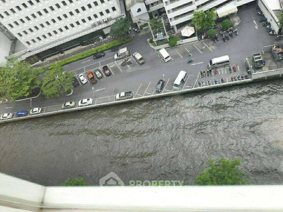 Aerial view of urban parking lot beside a canal with adjacent buildings.
