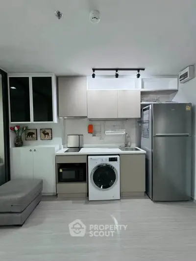 Modern compact kitchen with washing machine and sleek appliances in stylish apartment.
