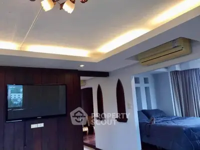 Spacious modern living room with stylish lighting and wall-mounted TV, adjacent to a cozy bedroom.