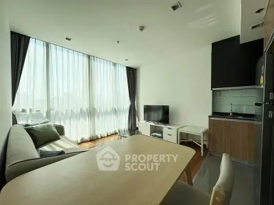Modern living room with open kitchen, large windows, and stylish furniture in a bright apartment.