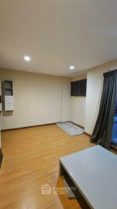 Spacious unfurnished living room with wooden flooring and large window.