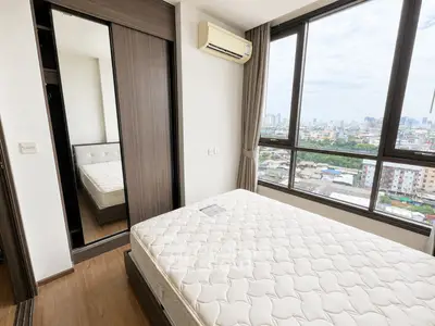 Modern bedroom with large windows offering stunning city views and ample natural light.