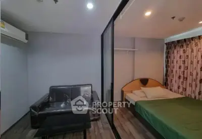 Modern studio apartment with glass partition, cozy bed, and sleek sofa in a stylish living area.